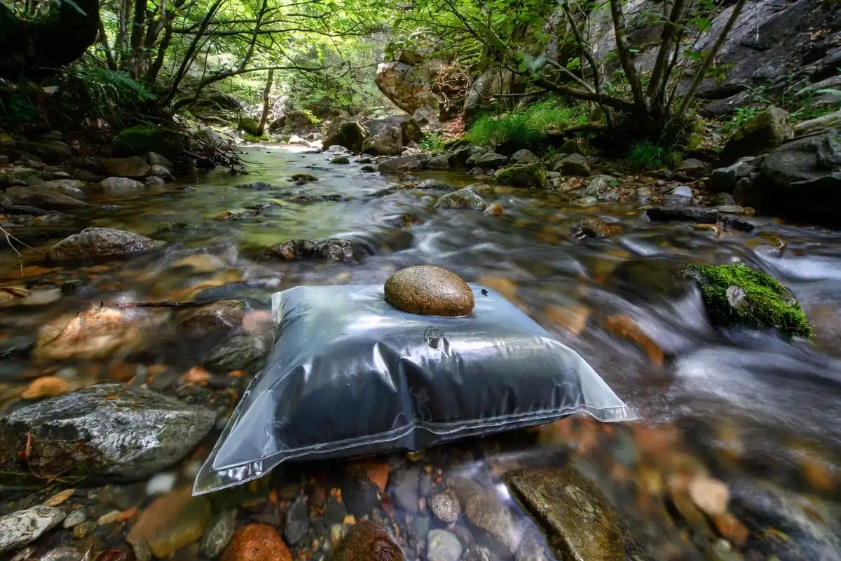  waterproof food bag anchored under cold running stream water in forest