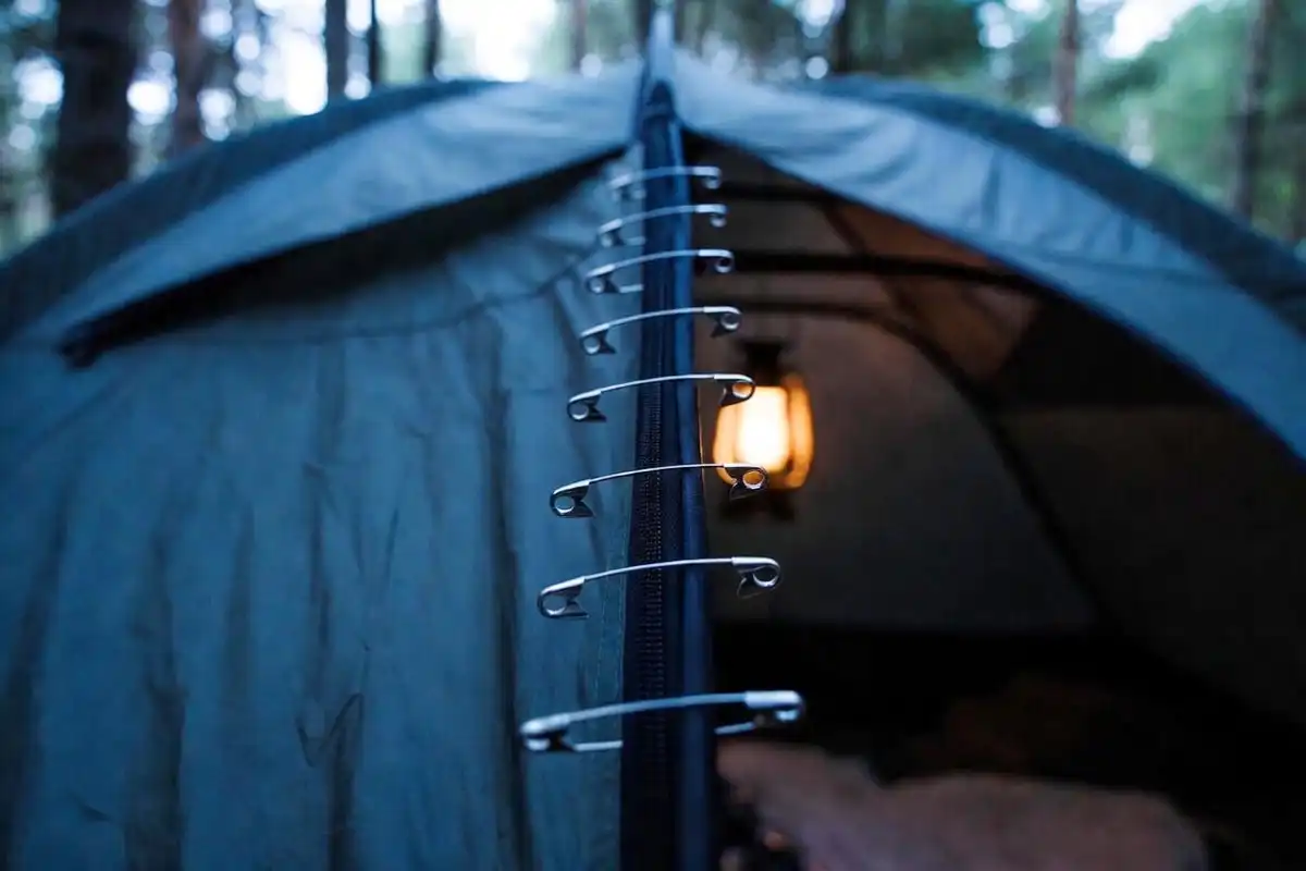 safety pins used to close a tent door gap as a temporary zipper repair at night camp