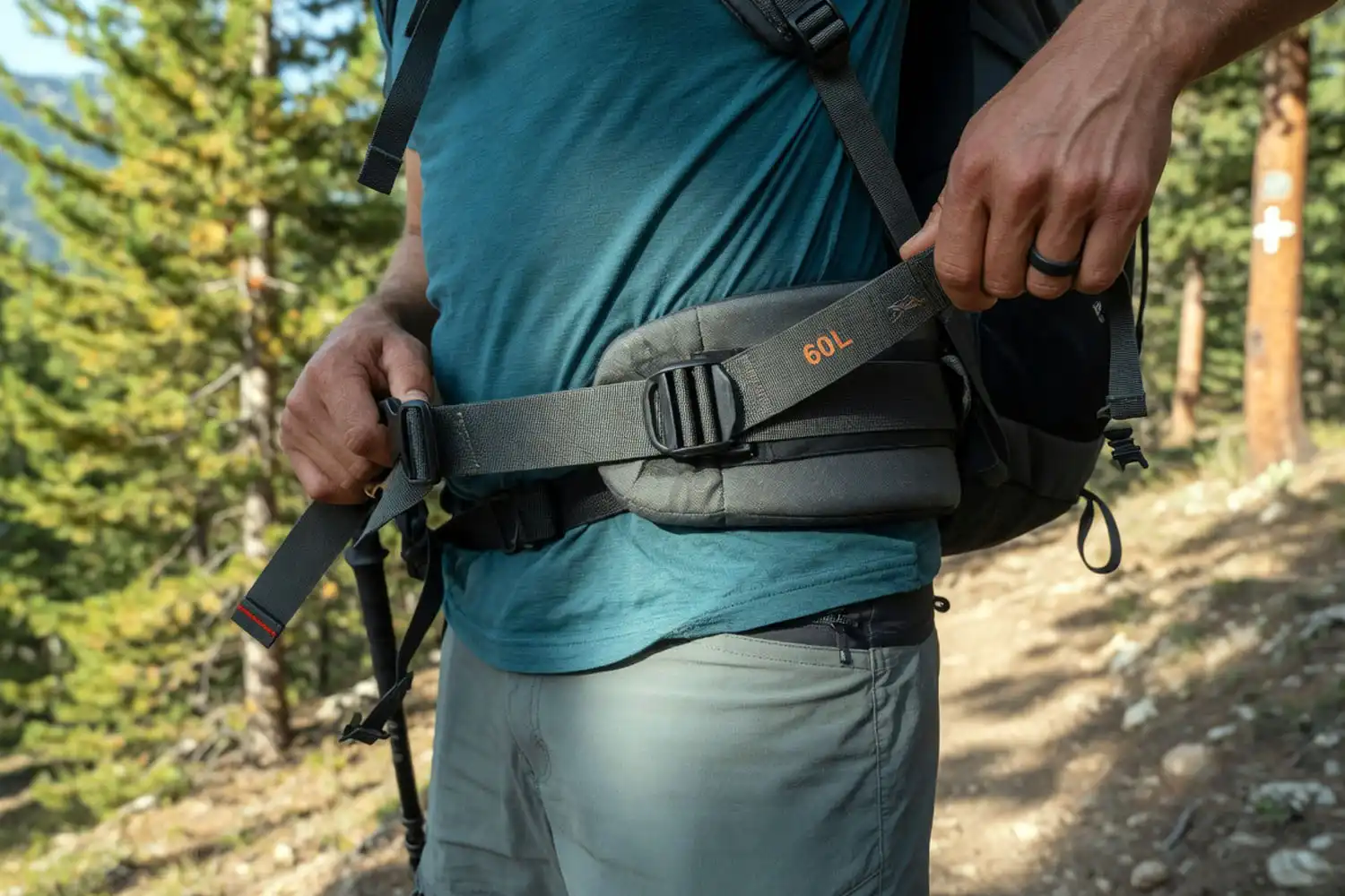 hiker tightening the hip belt of a loaded backpack to shift the load onto the hips
