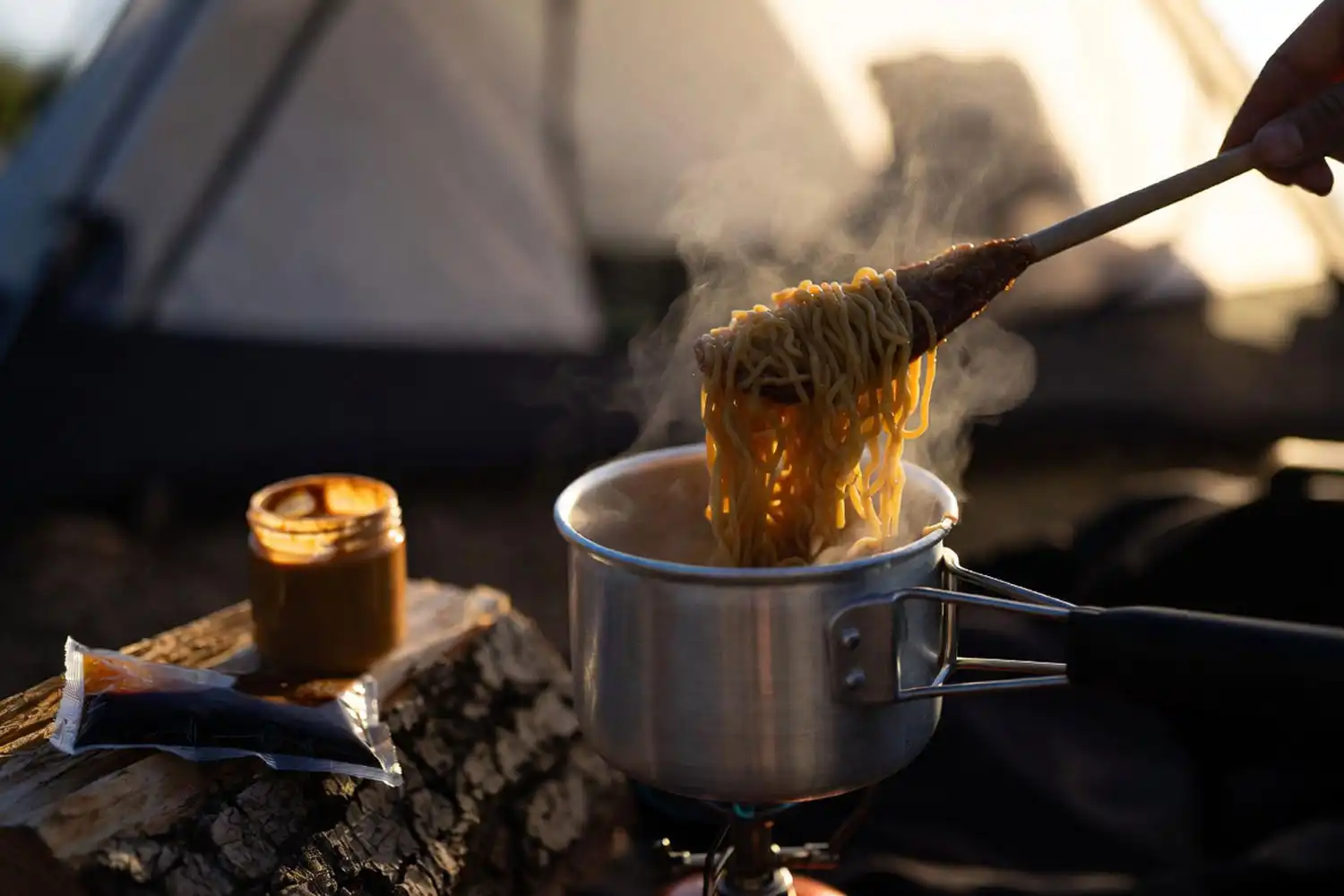 Small one liter pot of peanut noodles on a single burner camp stove at dusk